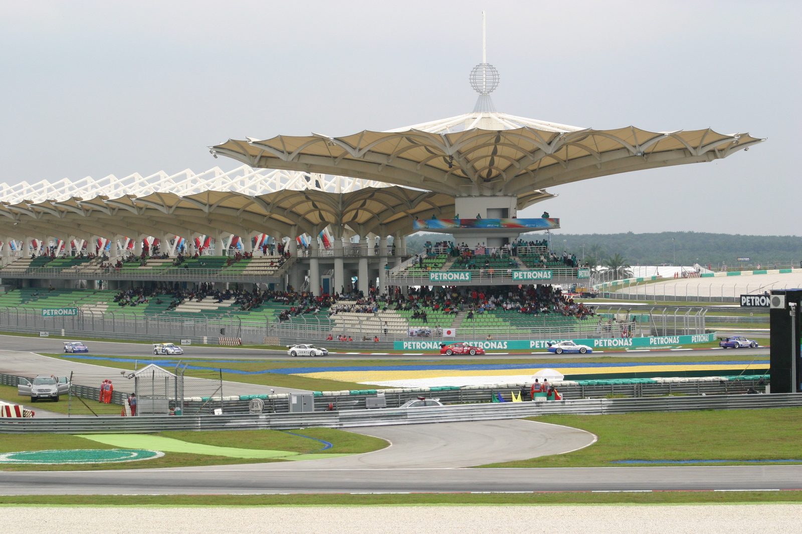 Race cars on track in front of the covered Sepang grandstands