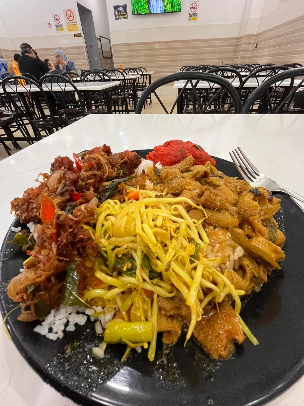 Nasi campur in a Kuala Lumpur food hall — tripe curry, bean sprouts, and the server who took charge of the plate.